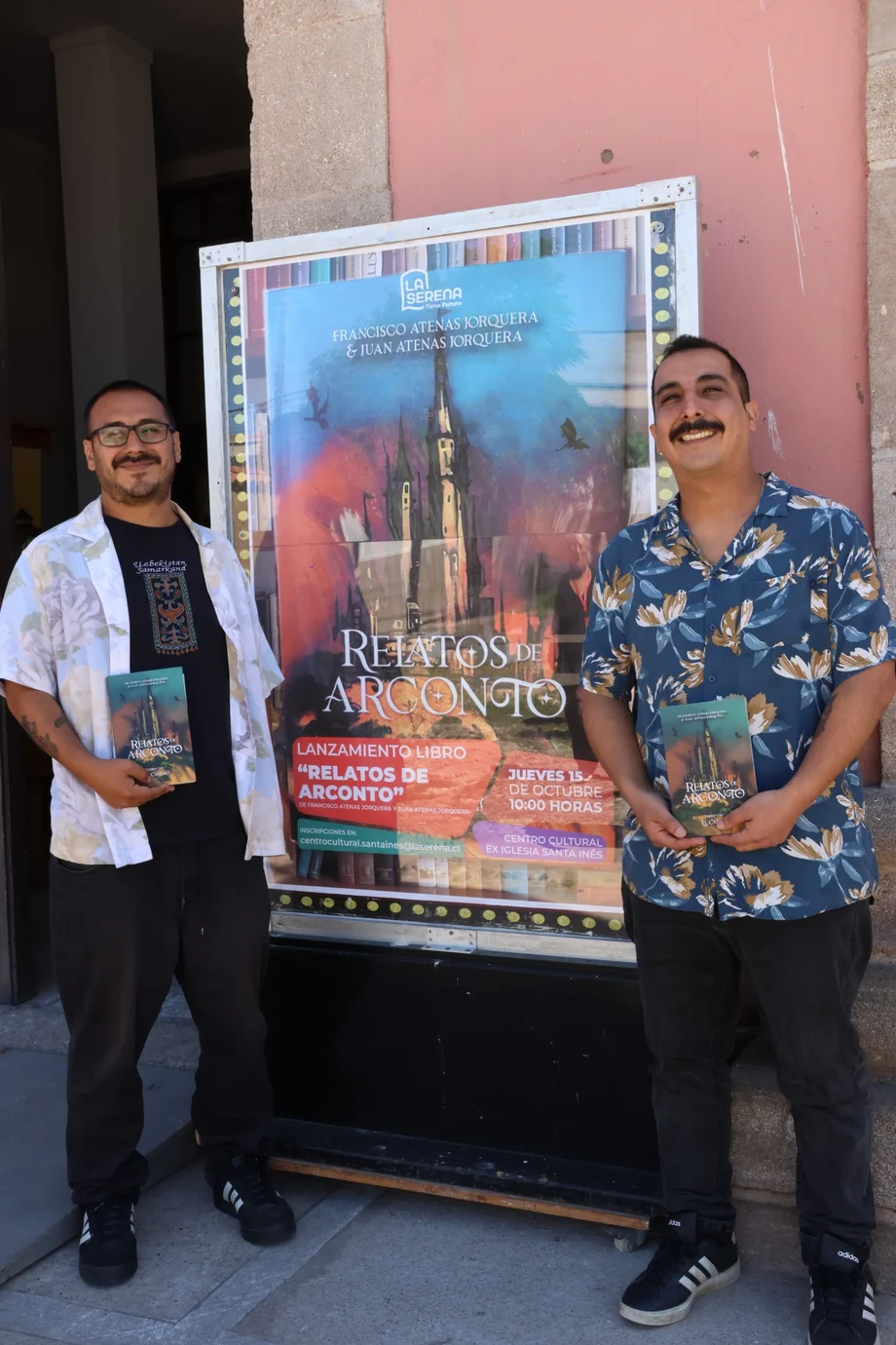 Francisco y Juan Atenas Jorquera junto al afiche de Relatos de Arconto durante el lanzamiento del libro